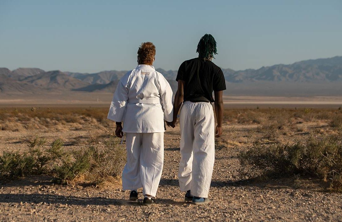 A grandson and his grandma walking in the desert wearing karate gear. Next Avenue