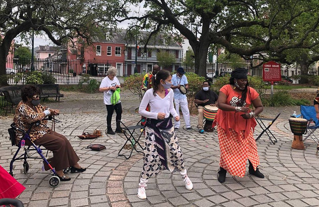 A group of people dancing with drums outside. Mardi Gras Indians, dancing, Next Avenue