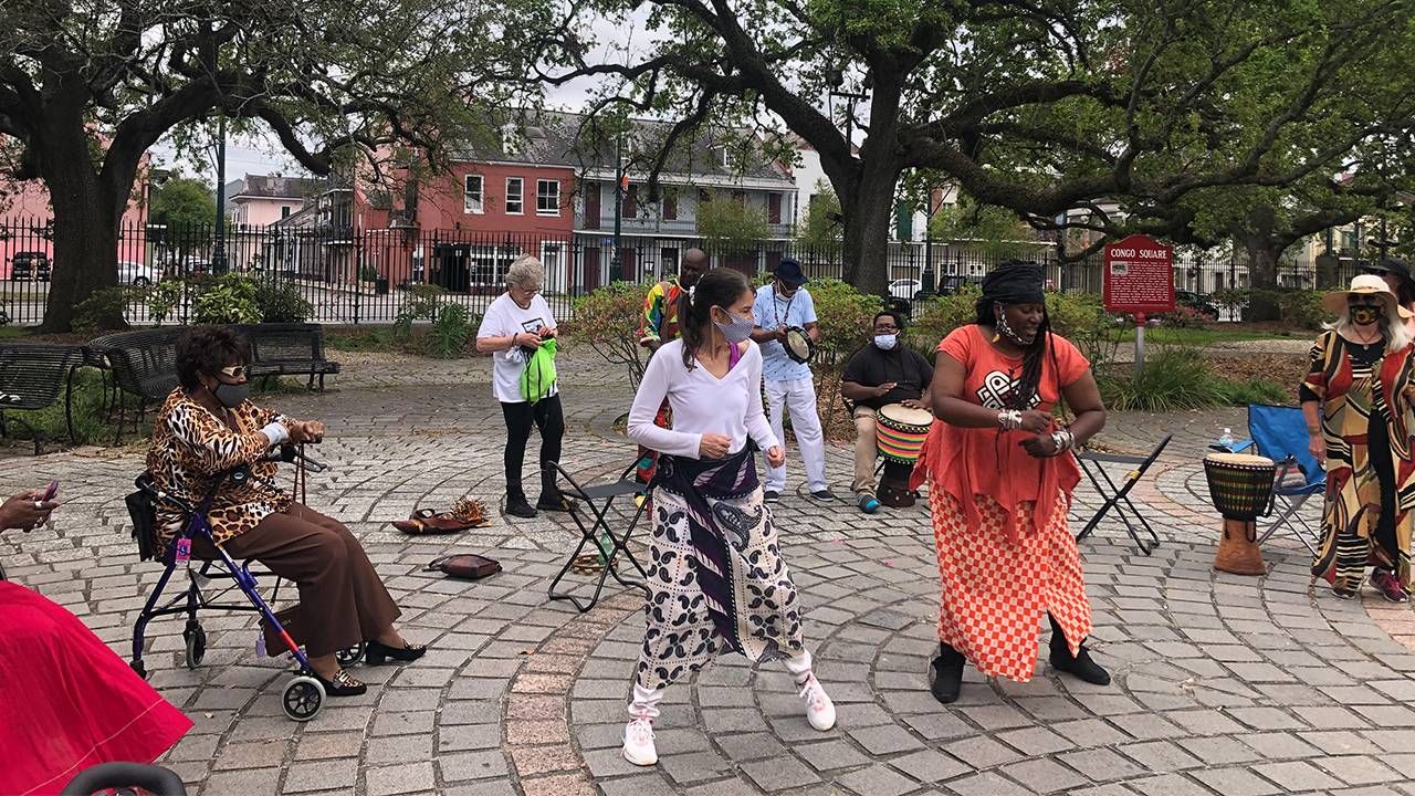 A group of people dancing with drums outside. Mardi Gras Indians, dancing, Next Avenue