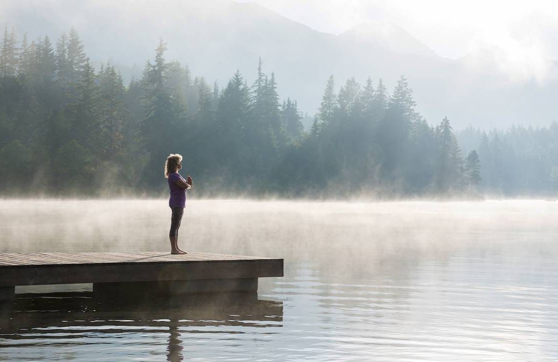 A woman meditating on the dock of a lake. life coach, powerful questions, PQsNext Avenue