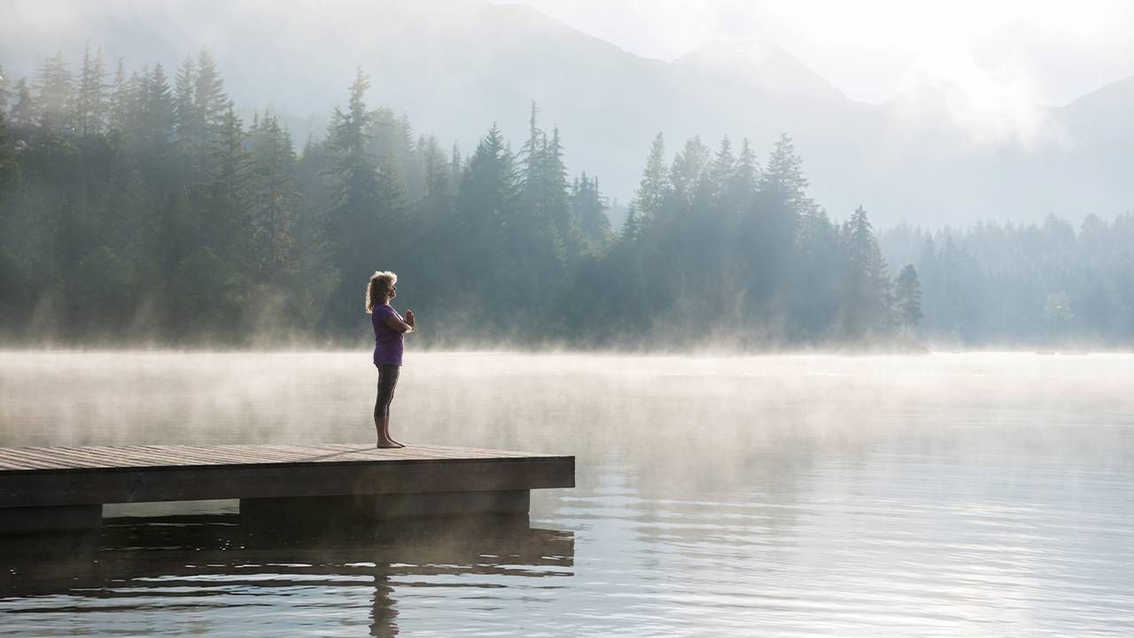 A woman meditating on the dock of a lake. life coach, powerful questions, PQsNext Avenue