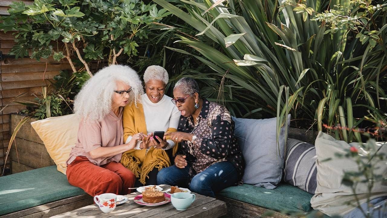 A group of friends laughing over coffee. friendship, Next Avenue