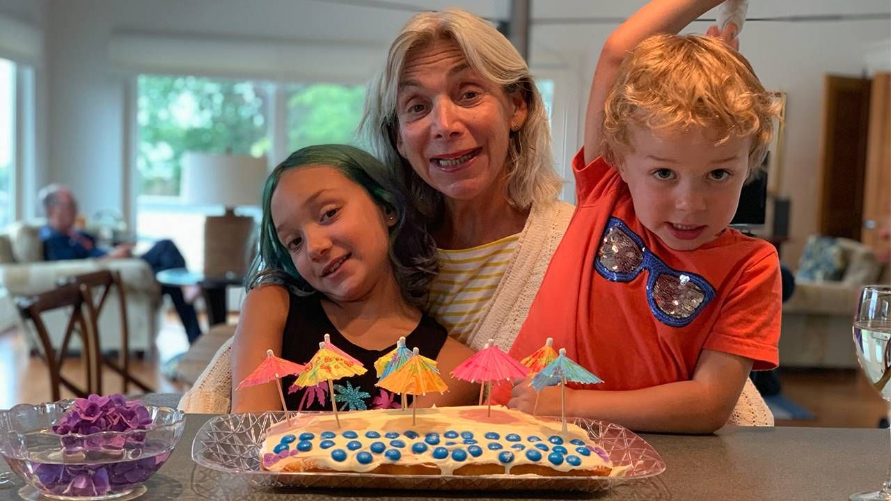 Freddi Greenberg and her grandchildren smiling in front of a cake. Next Avenue, grandparents, grandmother, grandchildren