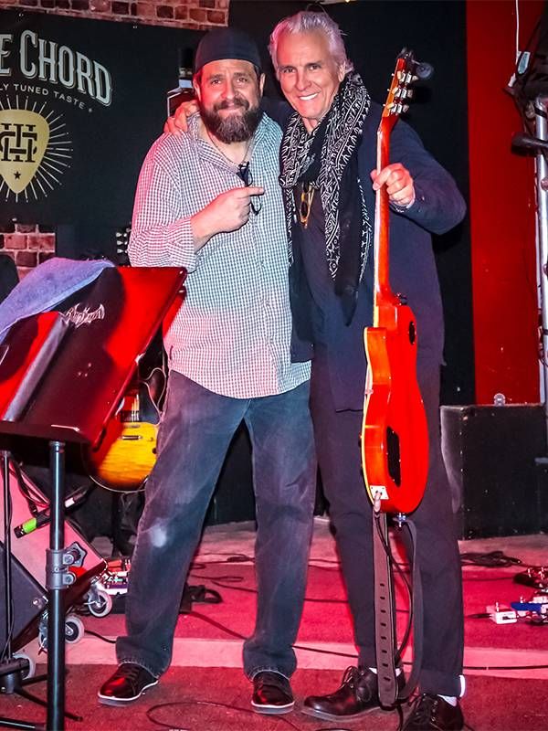 Two musicians standing on stage holding guitars. Music, Neil Giraldo, Next Avenue