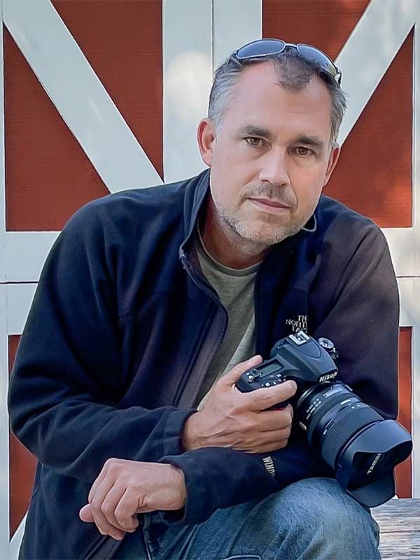 The photographer in front of a red and white barn door. photography, Next Avenue