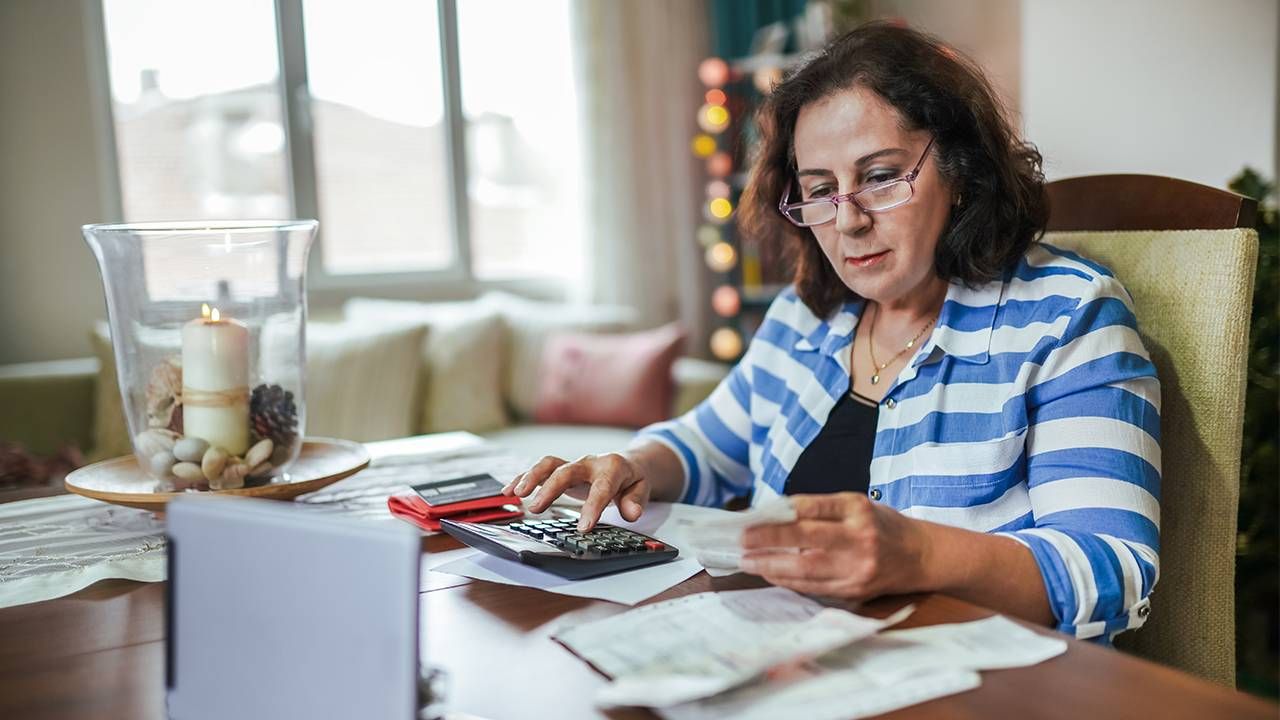 A woman sitting down to calculate her finances. Retirement savings, Next Avenue
