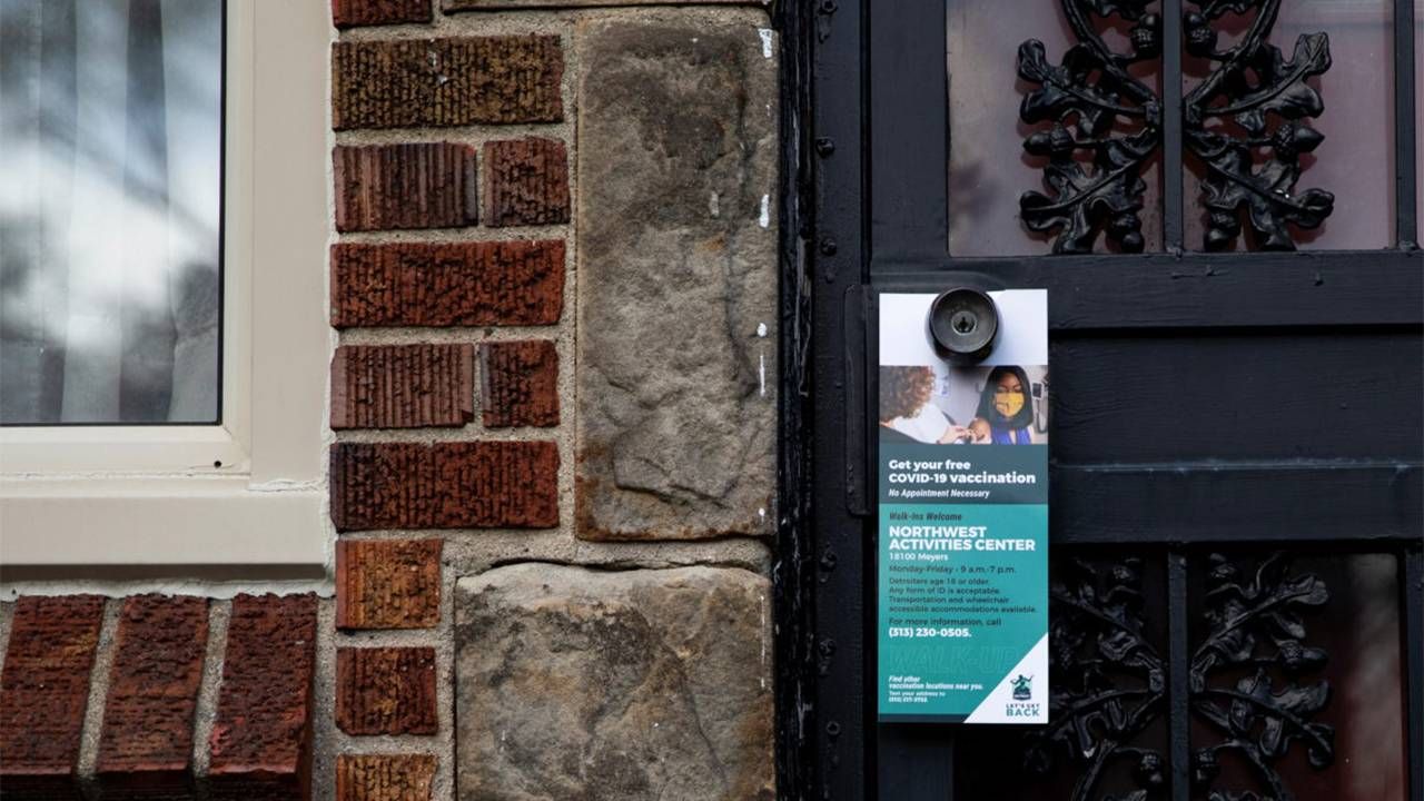 A door knocker hanging on a door knob to get the word out about getting the COVID-19 vaccine. Vaccine hesitancy, Next Avenue