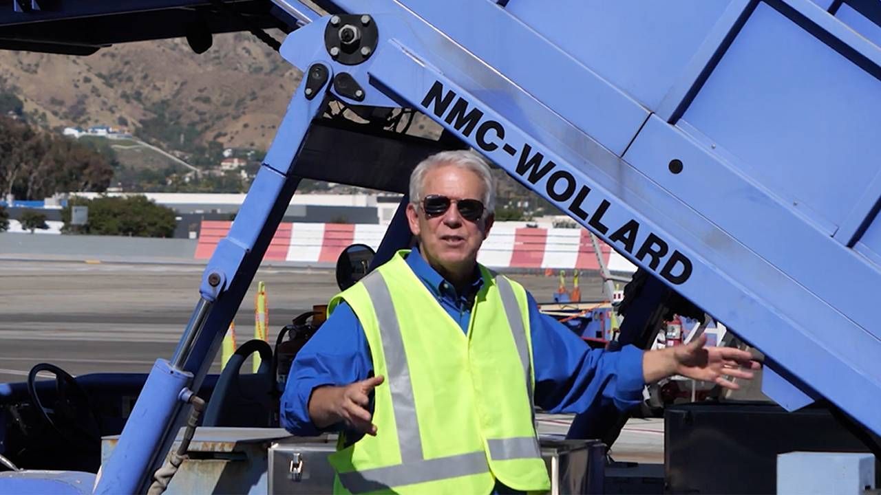 Pat Pattison wearing a yellow vest on an airport tarmac. Next Avenue, social media