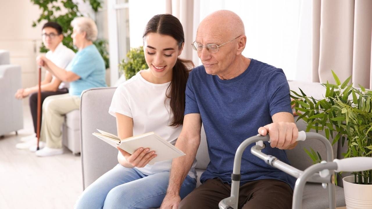 a younger woman and and older gentleman look together at a book