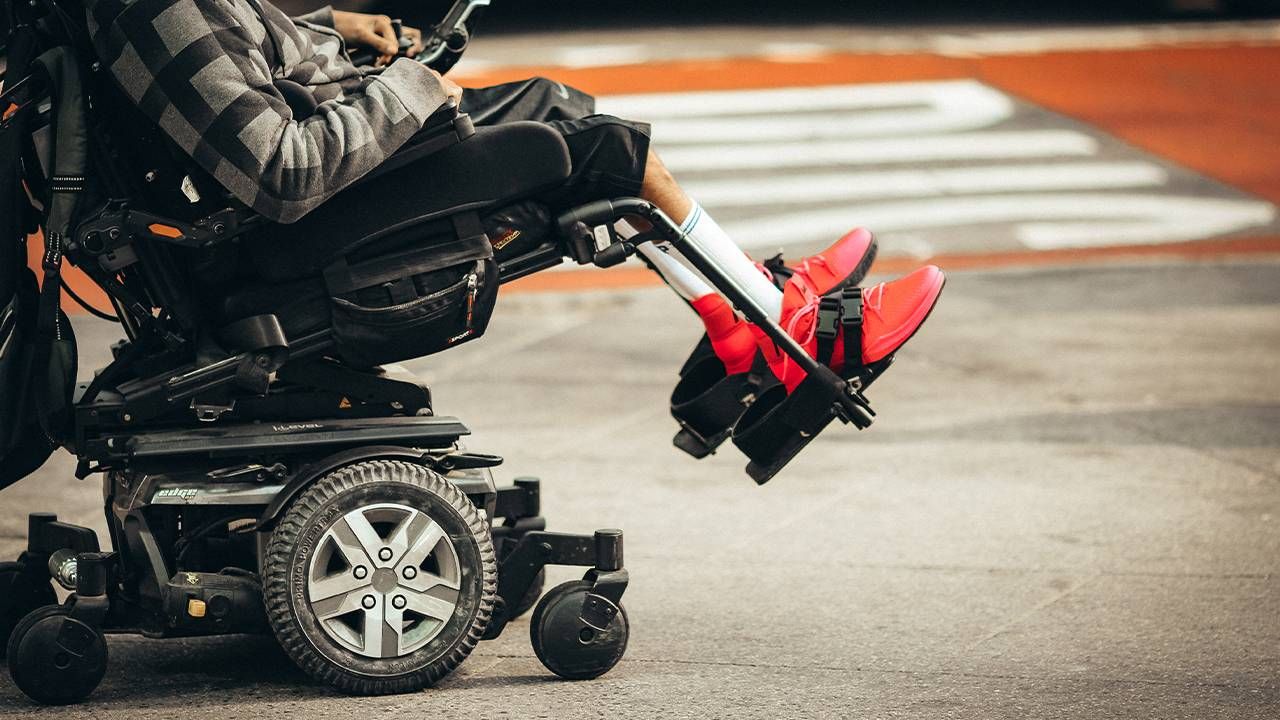 A closeup of a motorized wheelchair with a person sitting in it. Next Avenue, wheelchair damage, airport
