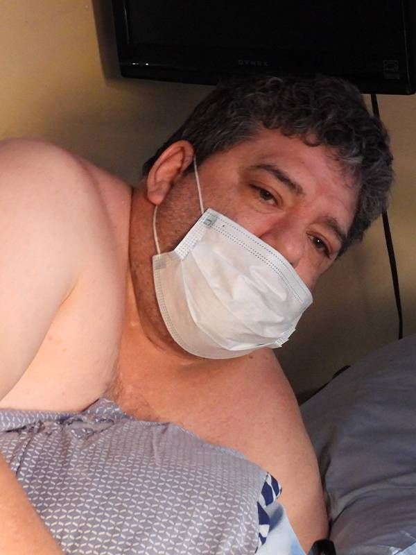 A man wearing a face mask looking sick in bed. Next Avenue, COVID-19, caregiving, native american elders
