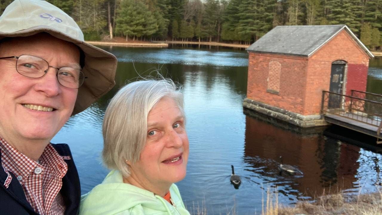 Lee and Linda Hilliard near a lake and evergreen trees. Next Avenue, climate change, stock, investments, green investing