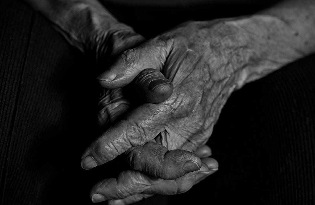 A close up shot of hands clasped in black and white. Next Avenue, isolation, loneliness, end of life