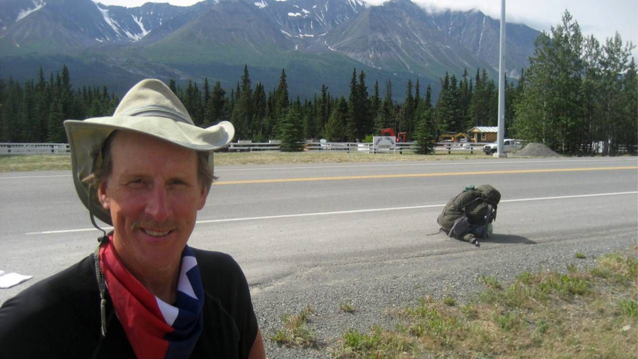 Michael Sean Comerford standing on the side of the road with a backpack. Next Avenue, route 66, carnival