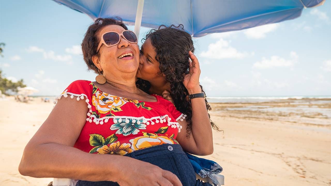 A grandchild kissing her grandmother on the cheek. Next Avenue, living in the moment