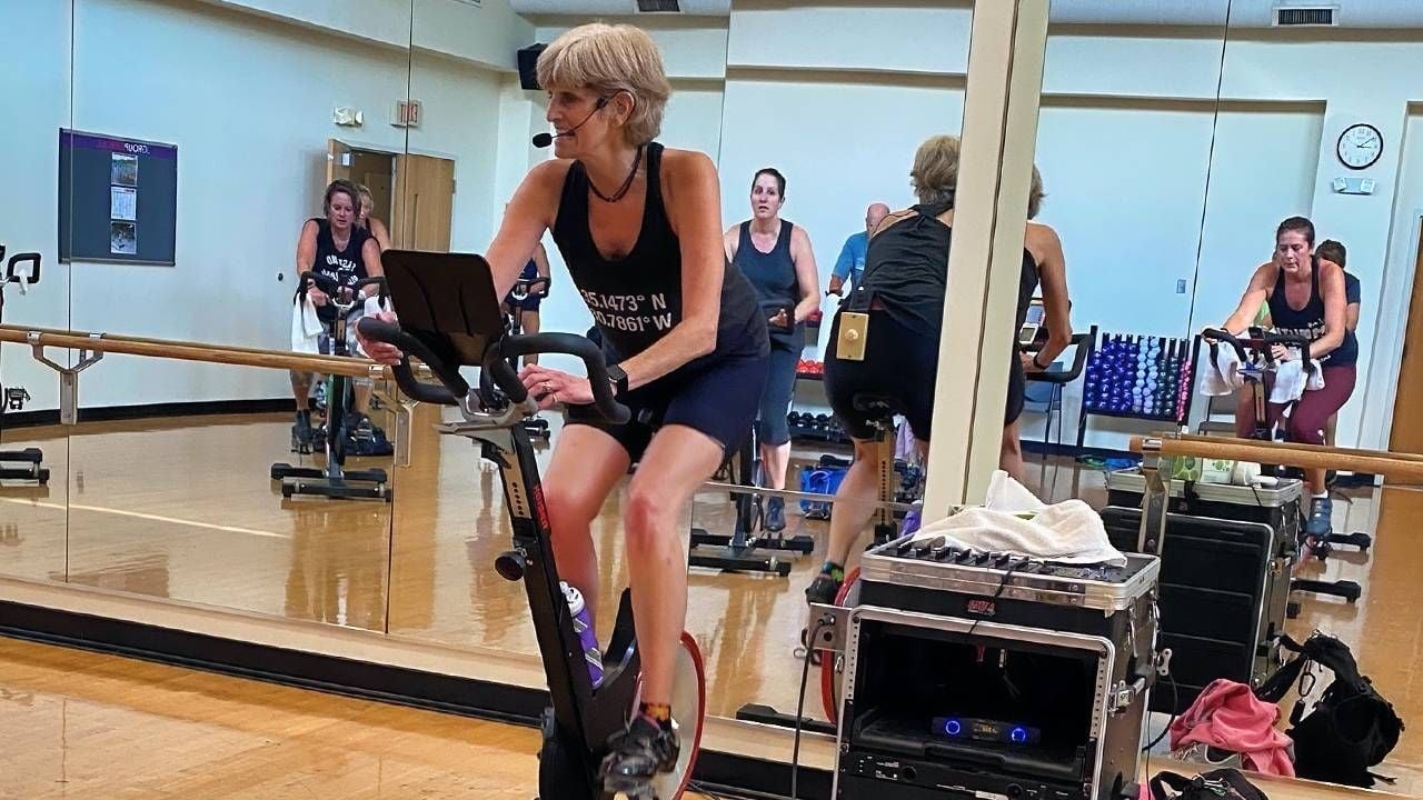 An older fitness trainer teaching a cycling class. Next Avenue