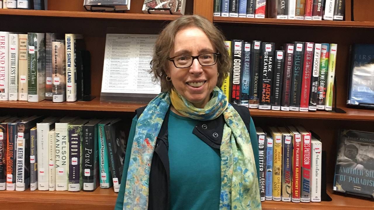 The author standing in front of a bookshelf at the library. Next Avenue