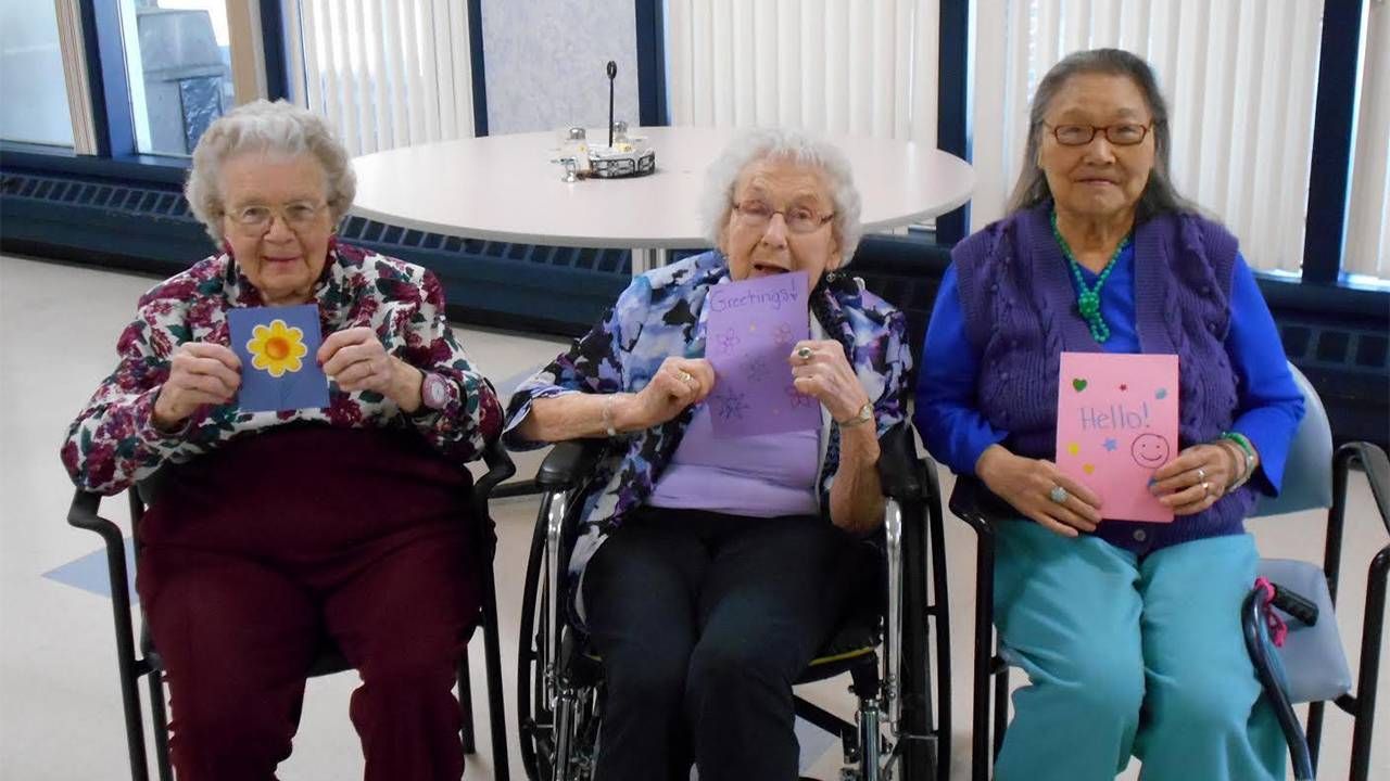 Three older woman holding letters sent by volunteers. Next Avenue