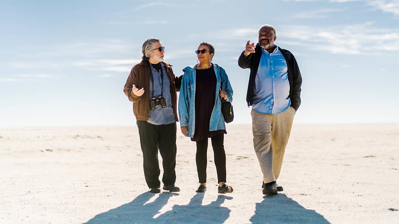 A group of older adult friends walking on beach. Steven Petrow, Next Avenue