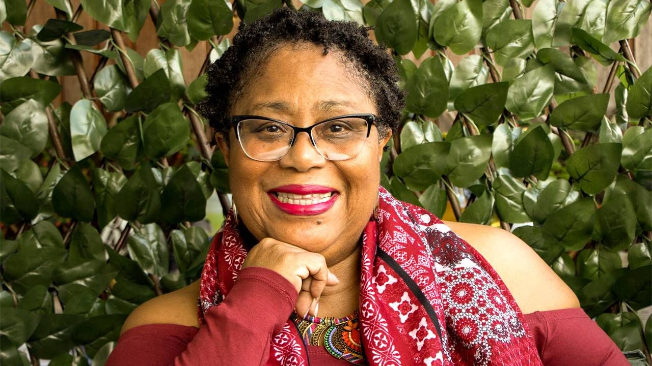 Author Dahlma Llanos-Figueroa wearing a red shirt and scarf. Next Avenue, Daughters of the Stone, afro-latina author