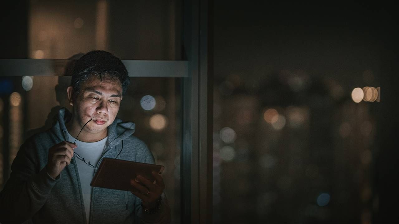 A man reading the news on his phone and looking worried. Next Avenue, emotion, money, investments