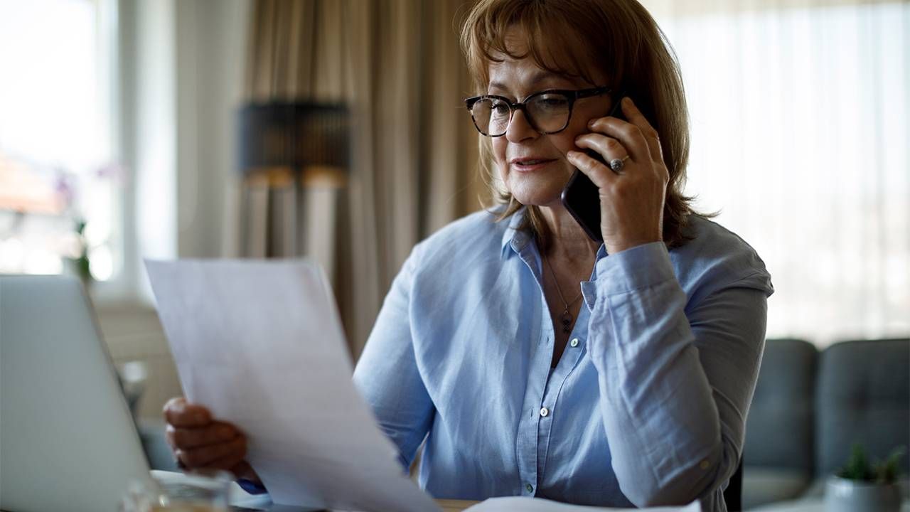 A woman on the phone and reading documents. Next Avenue, estate planning, long term care plan