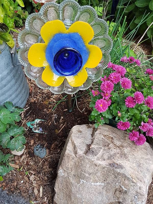 A flower made of old dishes in a garden. Next Avenue, vintage, repurposing, crafts