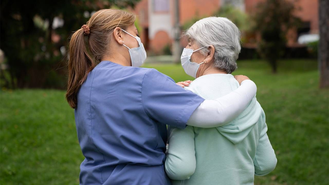 A paid caregiver walking with a patient. Next Avenue