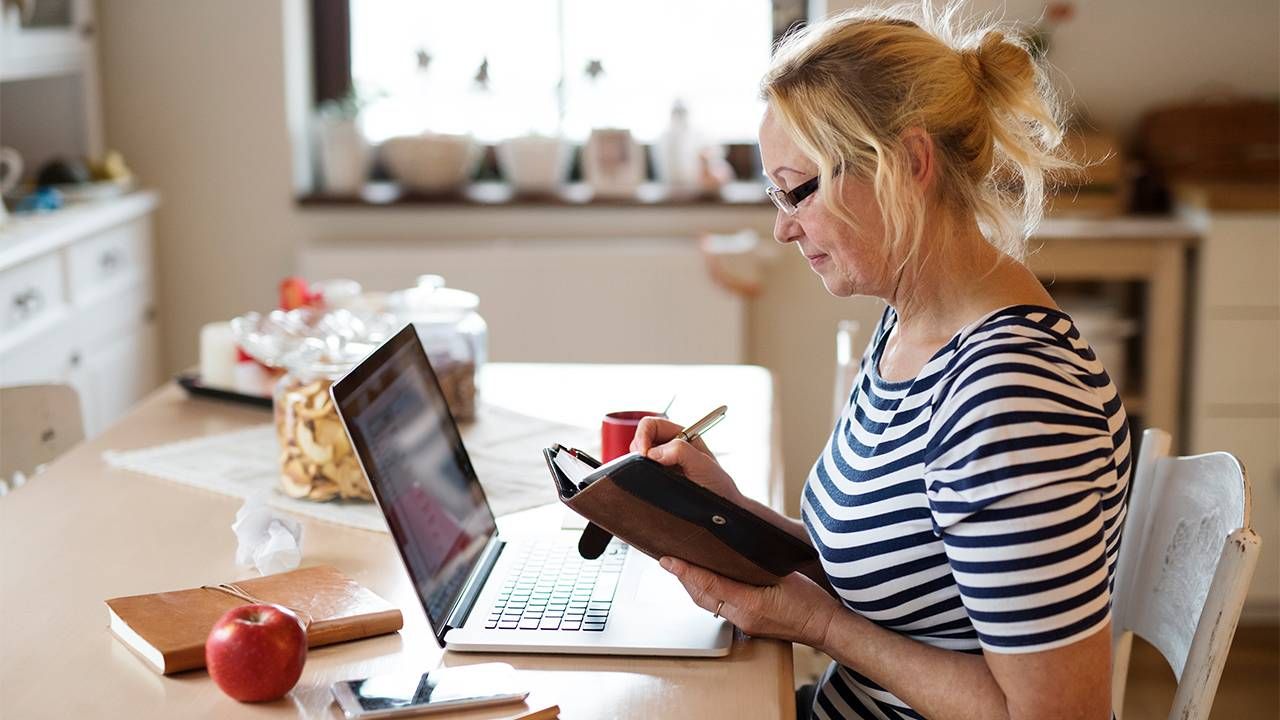 A woman writing out her schedule and looking on her computer. Next Avenue, montage career,