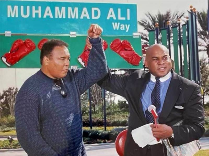 Reggie Williams holding up Muhammad Ali's hand during a ribbon cutting. Next Avenue, Muhammad Ali, PBS
