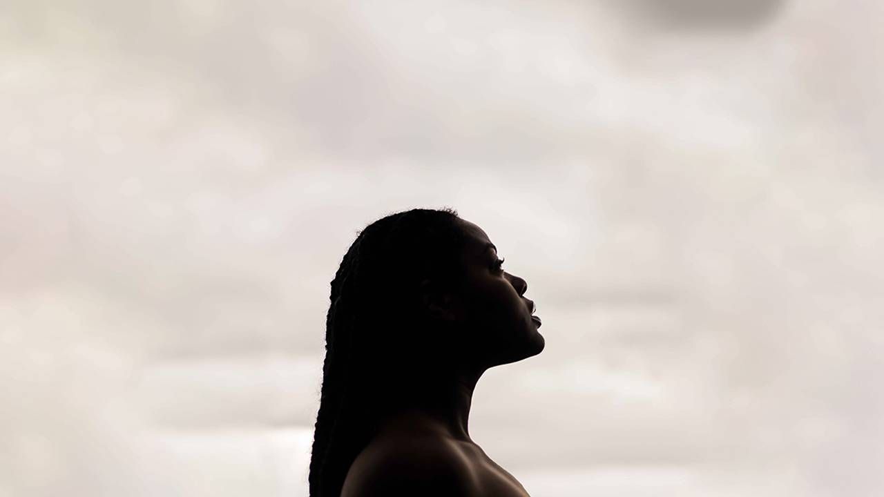 A woman looking up on a cloudy day. Next Avenue, mental health, Black women