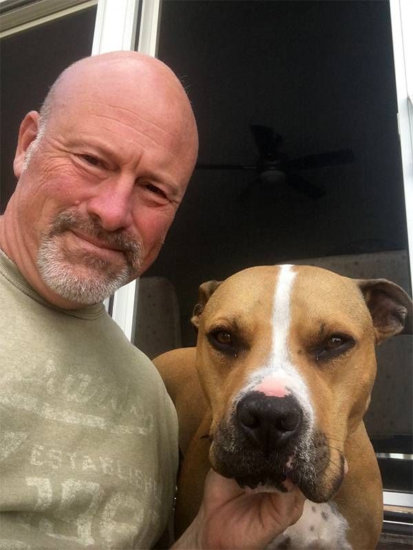 A man smiling and petting his dog. Next Avenue, anti social dog behavior, separation anxiety, pandemic dog