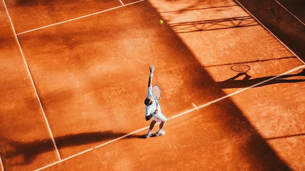 A man playing tennis on a clay court. Next Avenue