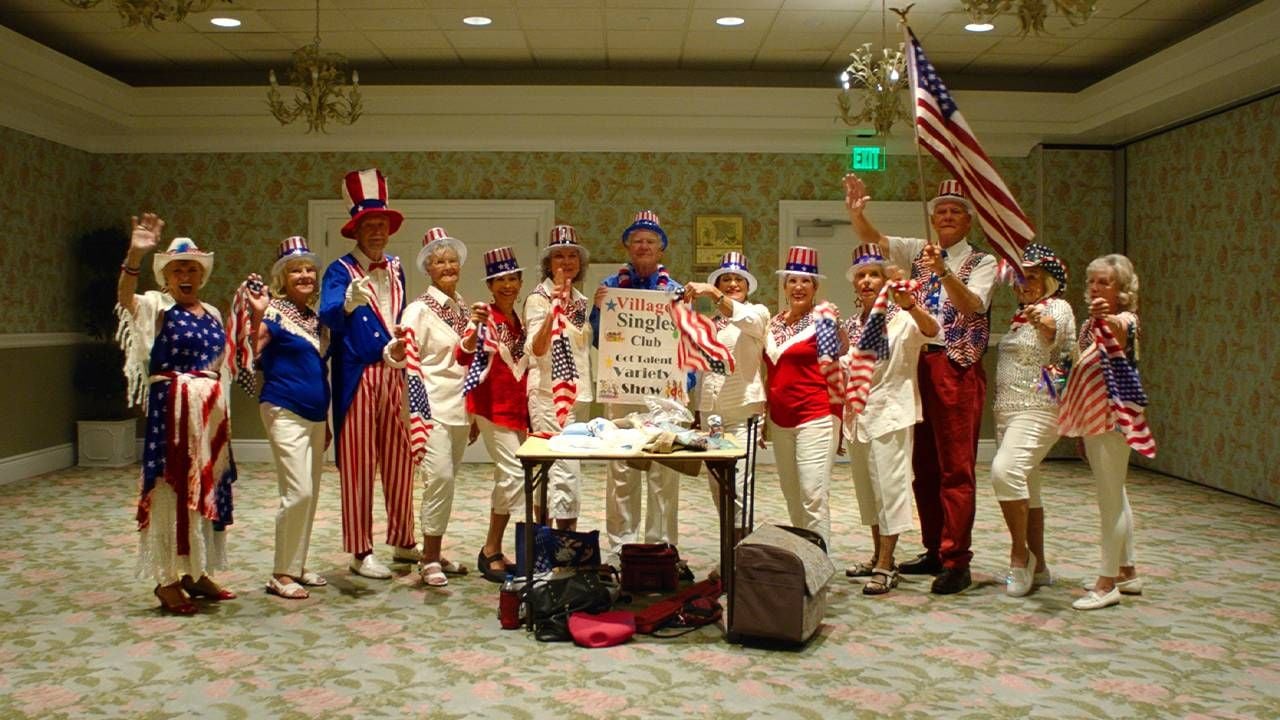 A group of older adults wearing patriotic clothing waving. Next Avenue, The villages, retirement community, diversity, intergenerational