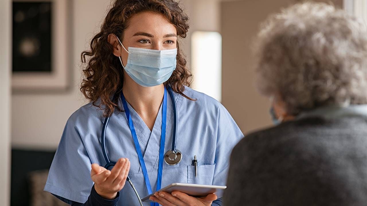 A nurse speaking to a nursing home resident and explaining something.