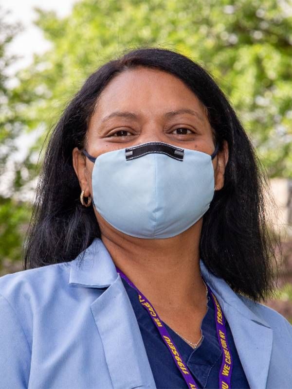 A person smiling underneath a face mask, wearing scrubs. Next Avenue, direct care workers, direct care workforce, staff shortages