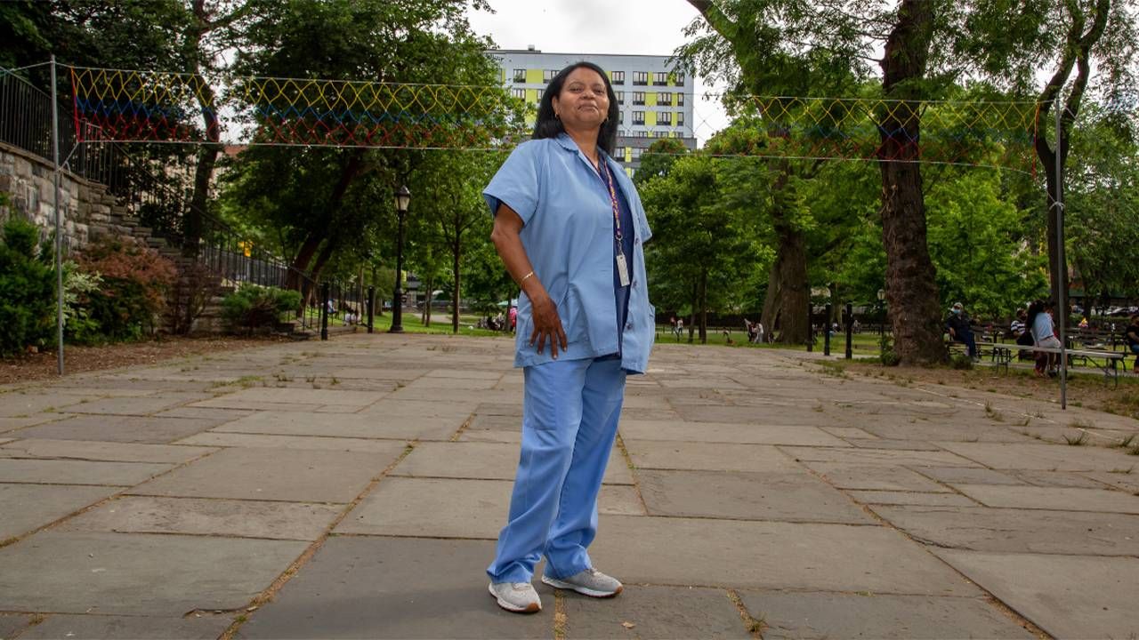A person wearing scrubs standing in a park. Next Avenue, direct care workers, direct care workforce, staff shortages