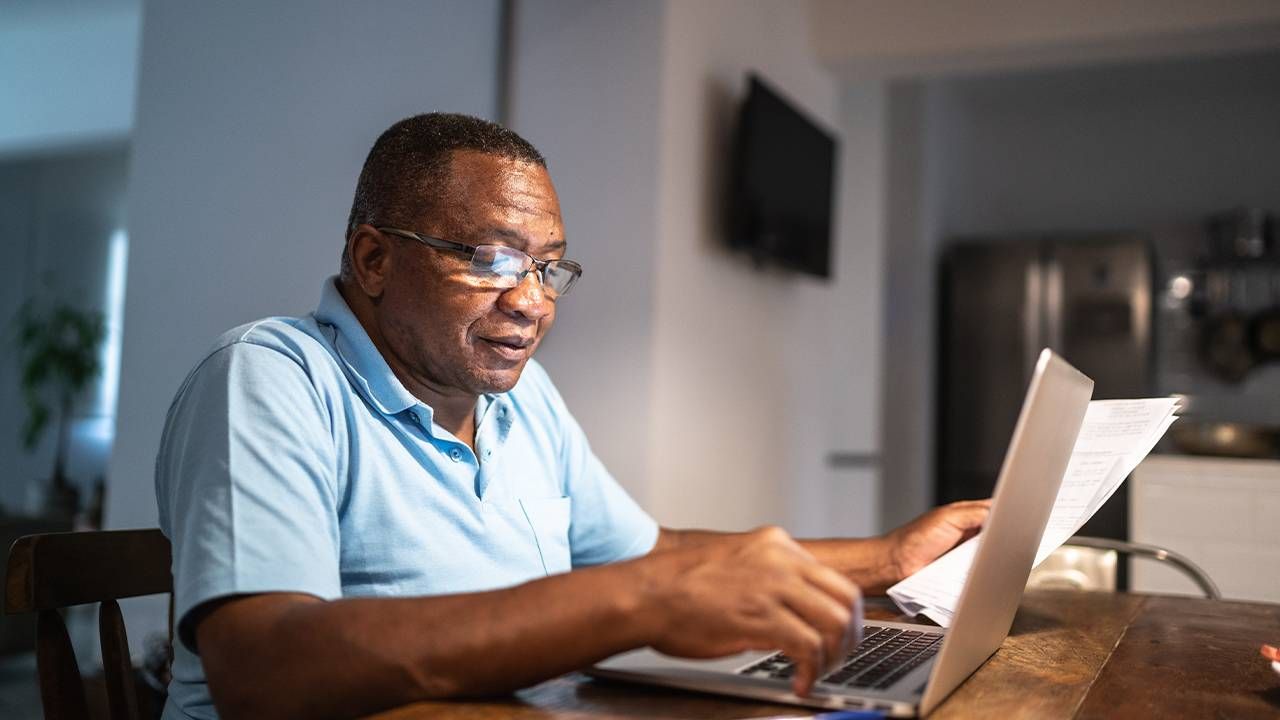 A man looking at an employee benefits package during open enrollment. Next Avenue, employee benefits open enrollment help