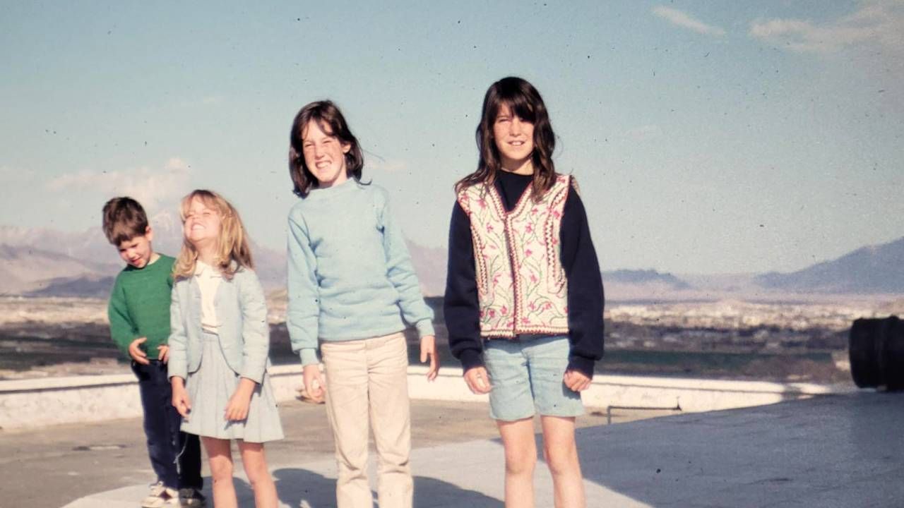 Four children smiling with a cityscape behind them. Next Avenue, Family trip, Afghanistan, Kabul