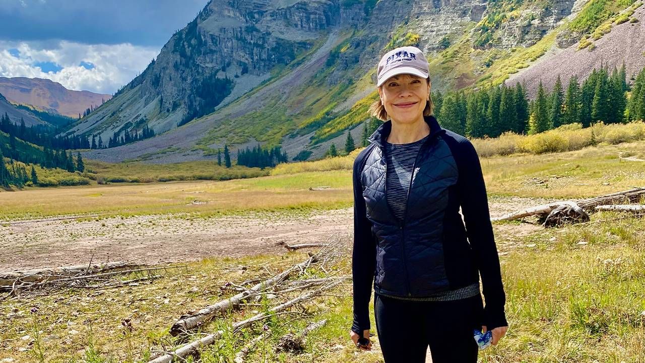 A woman standing outside in front of a mountain range. Next Avenue, meno-potbell, menopause body changes