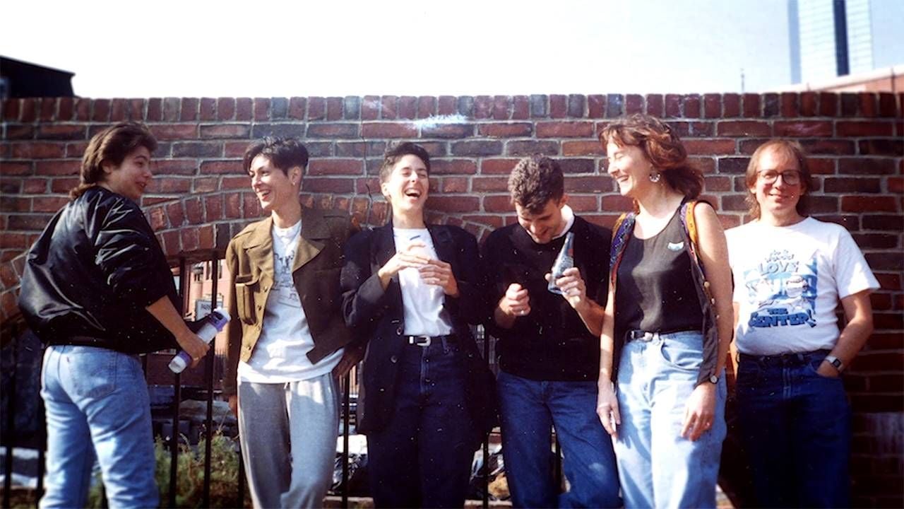 A group of comics laughing, standing against a brick wall. Next Avenue, queer comics, No Straight Lines