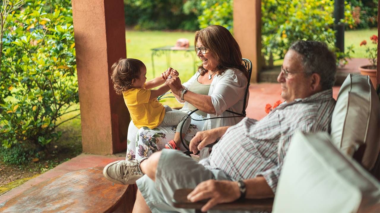 A couple sitting on the porch with their grandchild. Next Avenue, reverse mortgage