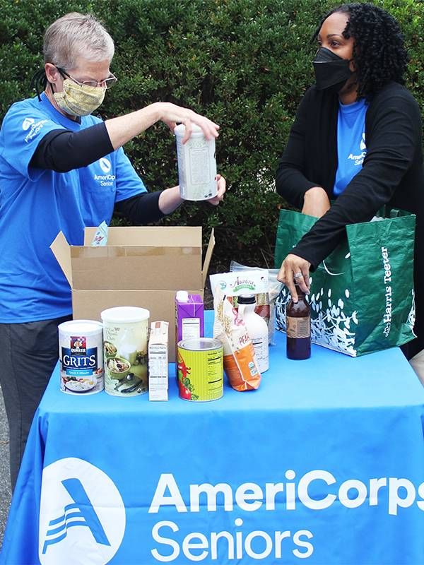 Two older adults bagging up groceries for AmeriCorps Seniors. Next Avenue