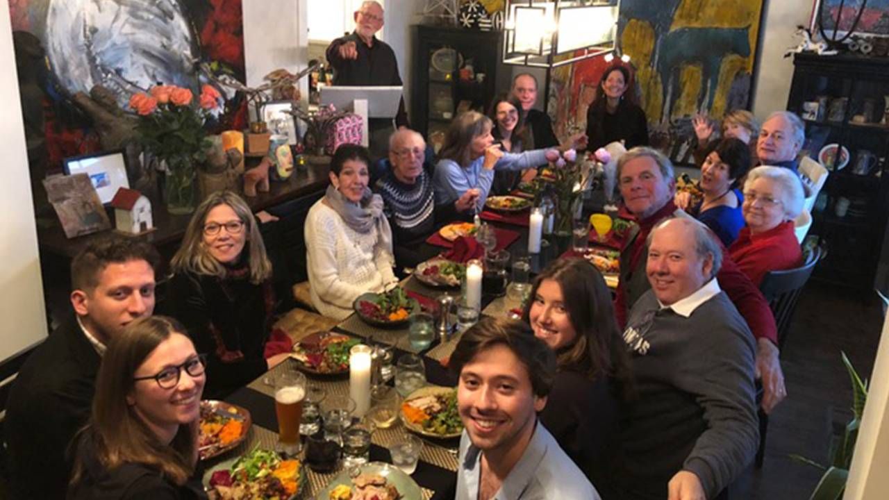 A large family gathered around a long dining table with festive decorations. Next Avenue, Hanukkah, Christmas Hybrid holiday