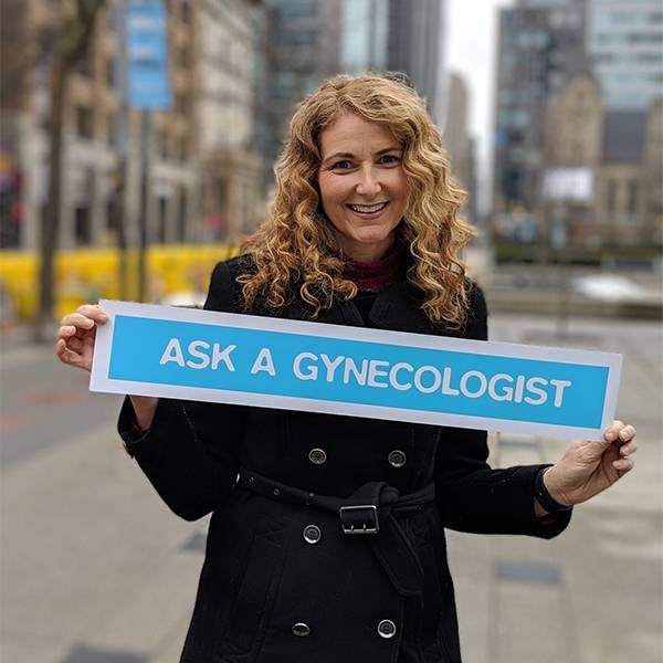 Headshot of woman holding a sign that says, "ask a gynecologist." a Next Avenue