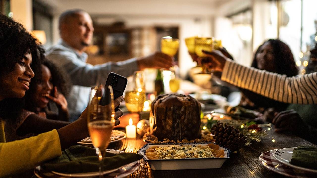 A family together at the table over a holiday meal, toasting. Next Avenue, covid-19, holiday, family