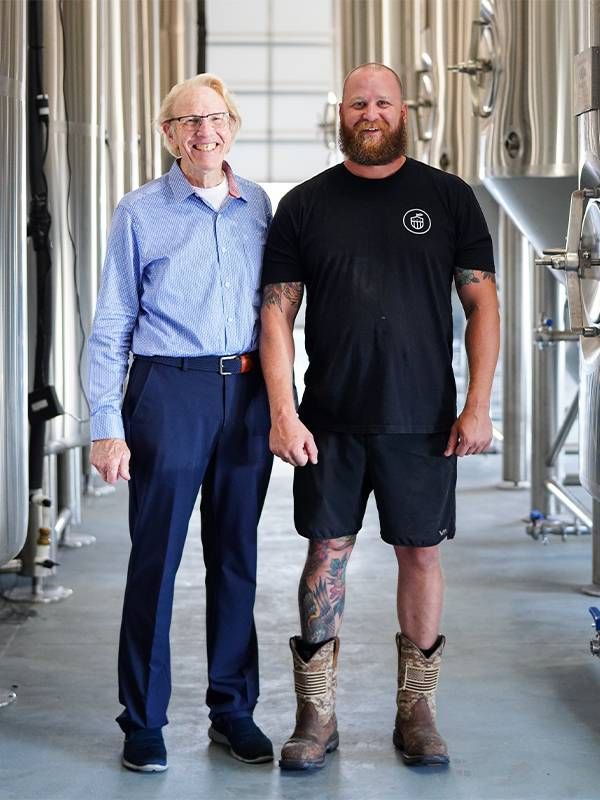 Two veterans standing next to each other in a craft cider factory. Next Avenue, veterans, vets, craft cider