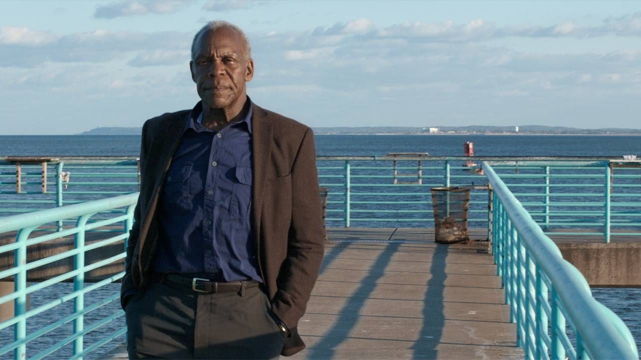 Danny Glover standing on a boardwalk near the ocean in The Drummer. Next Avenue