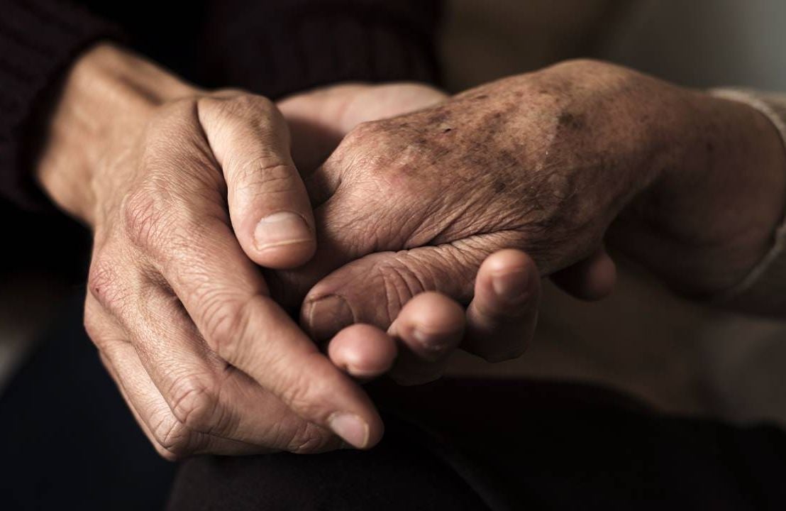 A caregiver holding hands with an older adult. Next Avenue, dying, death, caregiving