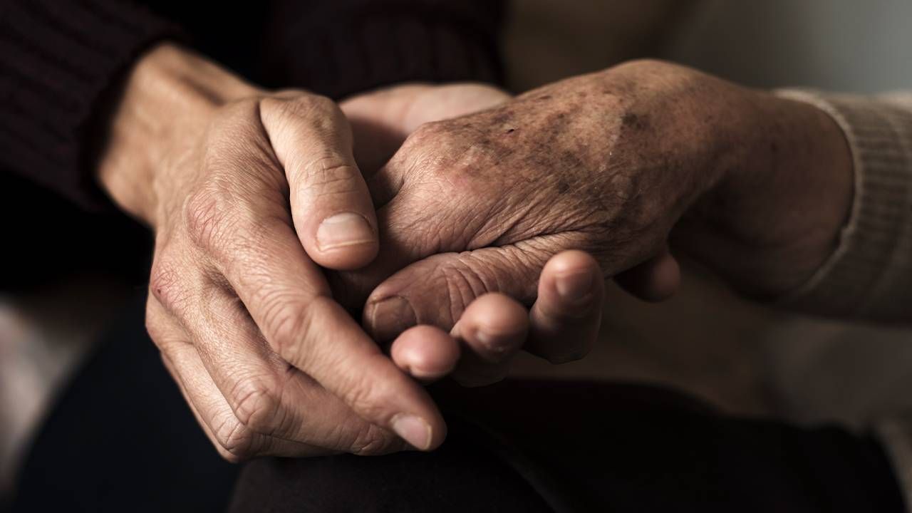 A caregiver holding hands with an older adult. Next Avenue, dying, death, caregiving